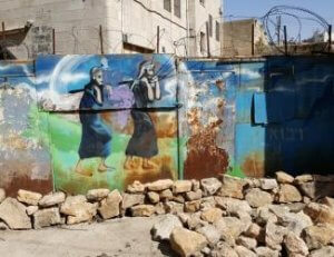 (Photo: Mural on a wall in Hebron's Old City depicting the scouts carrying grapes.)